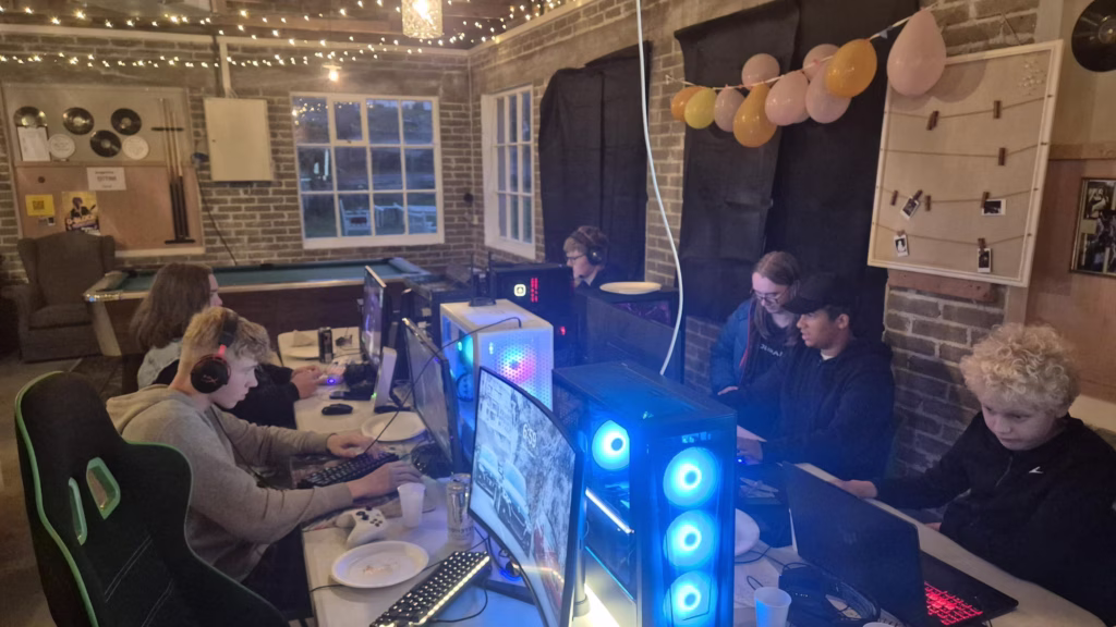 En gruppe barn sitter rundt et bord med PC-er